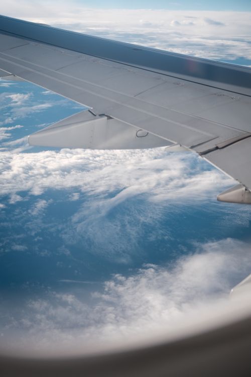 Free Aerial view of blue sky and clouds from an airplane window, featuring the aircraft wing. Stock Photo