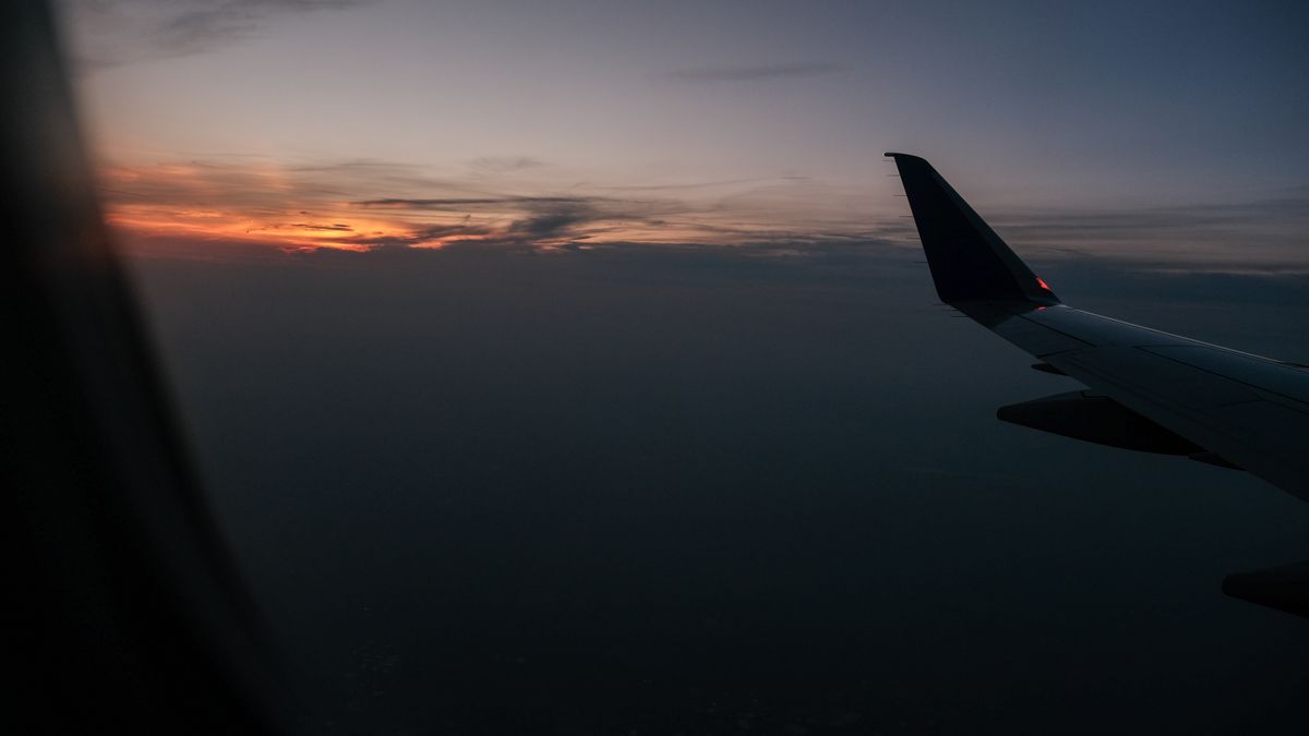 View of airplane wing against a vibrant sunset sky, captured during mid-flight.