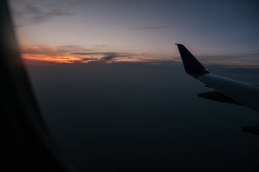 View of airplane wing against a vibrant sunset sky, captured during mid-flight.