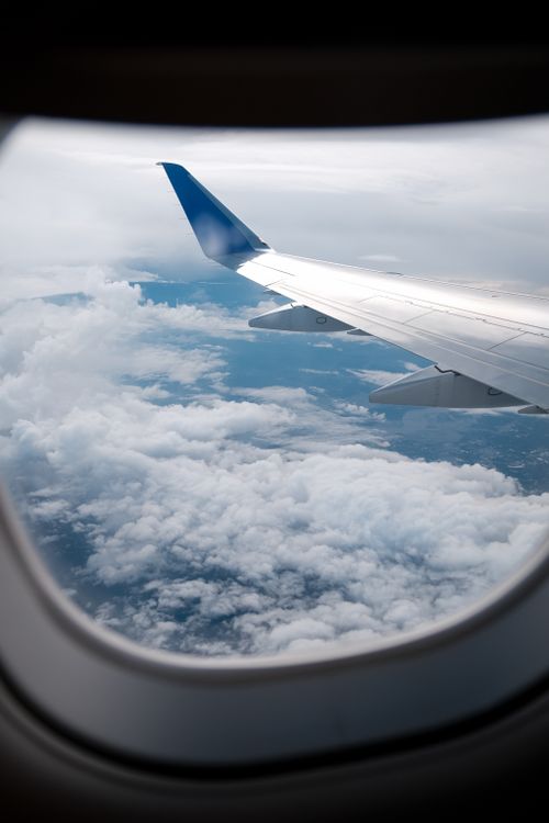 Free View from airplane window of wing and clouds below during flight. Stock Photo