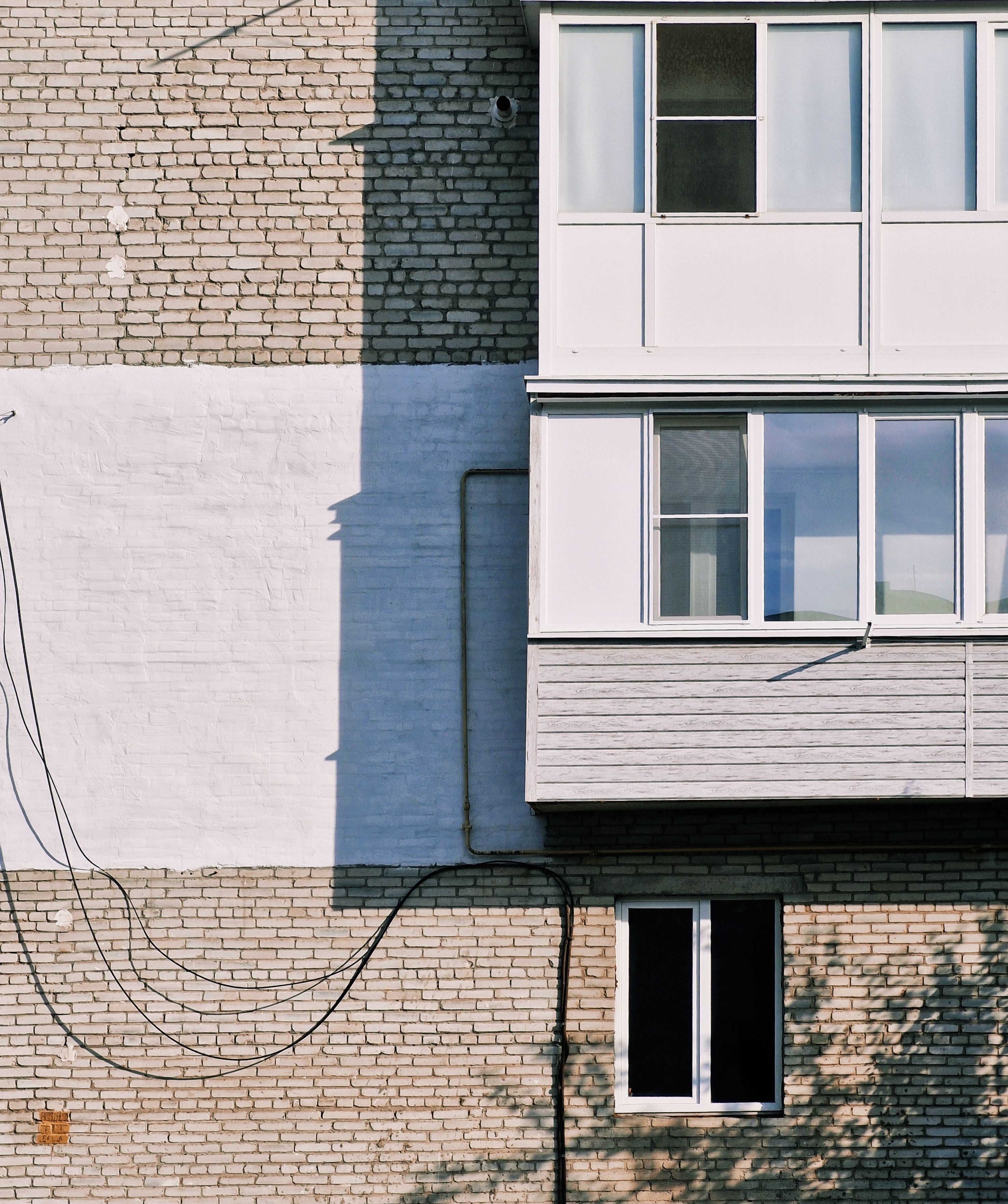 Close-up view of an urban building facade with brickwork and enclosed balcony.