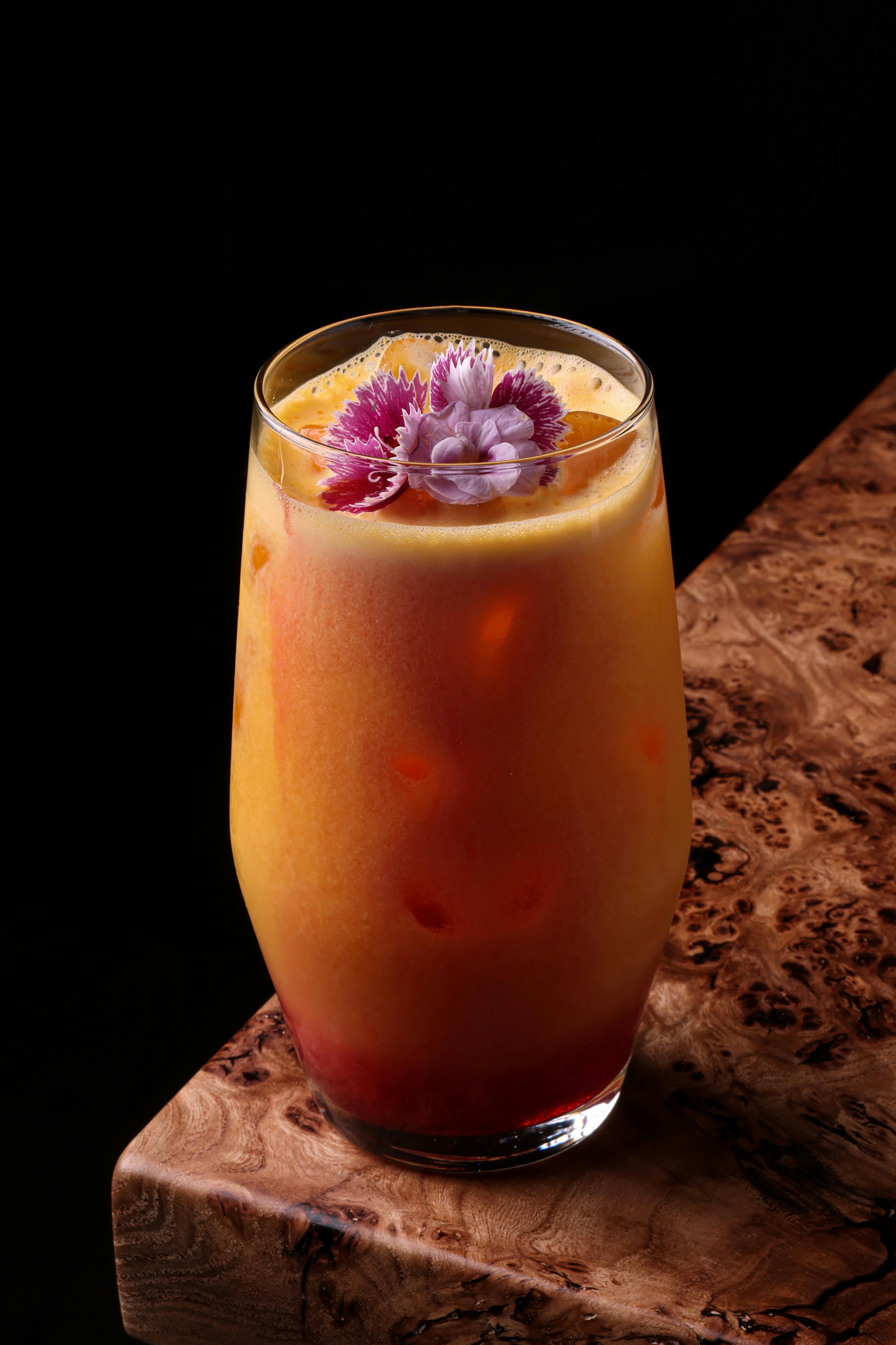 Vibrant citrus cocktail garnished with edible flowers, perfect for a refreshing summer treat.