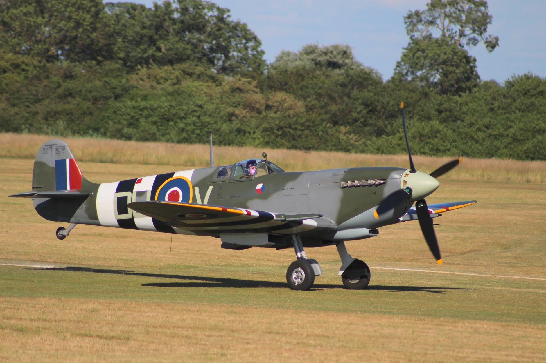 World War II era fighter plane on airfield runway during a sunny summer day.