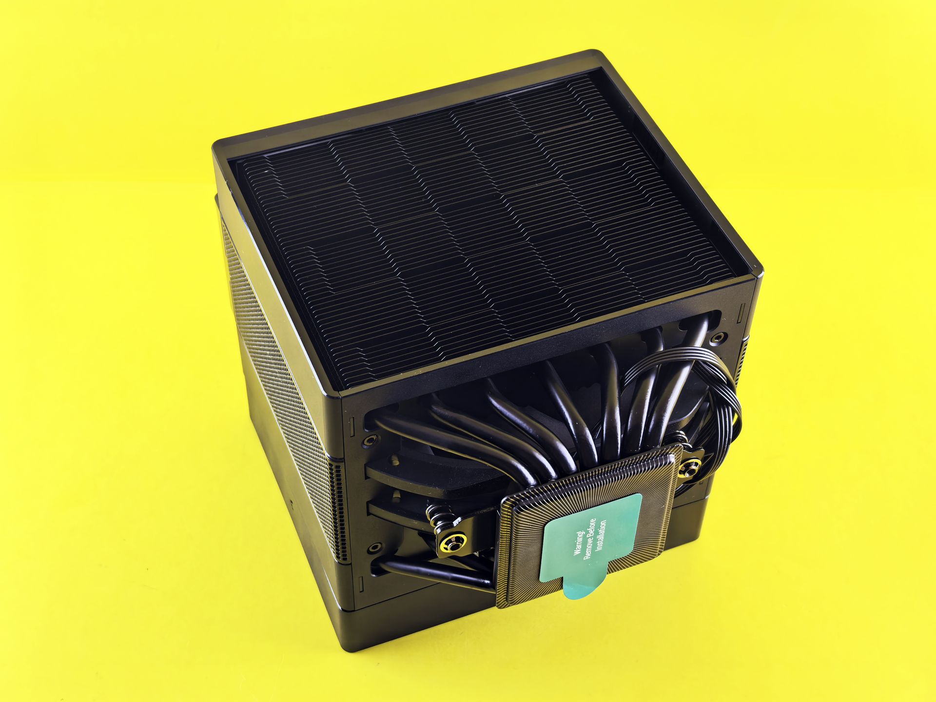 Black CPU cooler with intricate design showcased on a vibrant yellow background, emphasizing cooling technology.