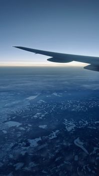 A breathtaking aerial view from an airplane window over a snow-covered landscape at dawn.