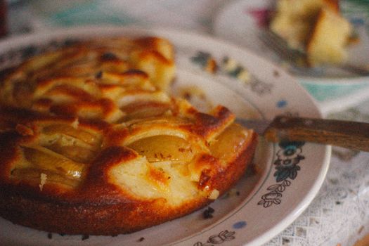 Close-up of a rustic homemade apple pie on a vintage patterned plate, evoking a warm, cozy mood.