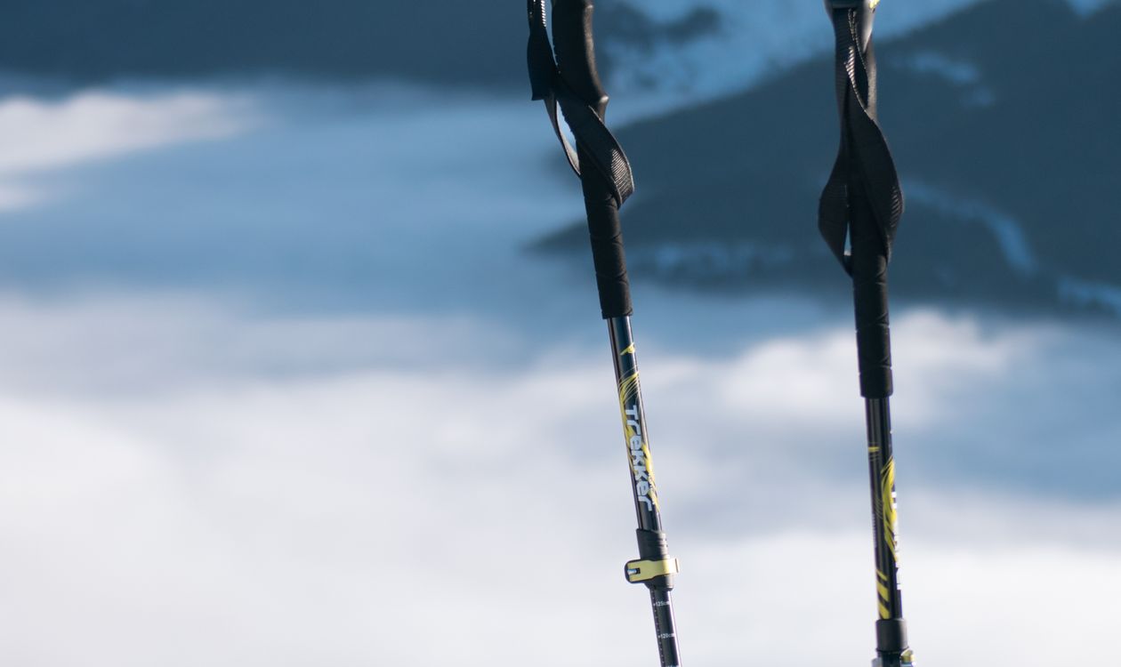 A pair of trekking poles and a black backpack stand upright on a snow-covered ridge against a backdrop of snow-capped mountains, illustrating the typical outdoor backpack product that drives MOQ negotiation between B2B buyers and Chinese mills.