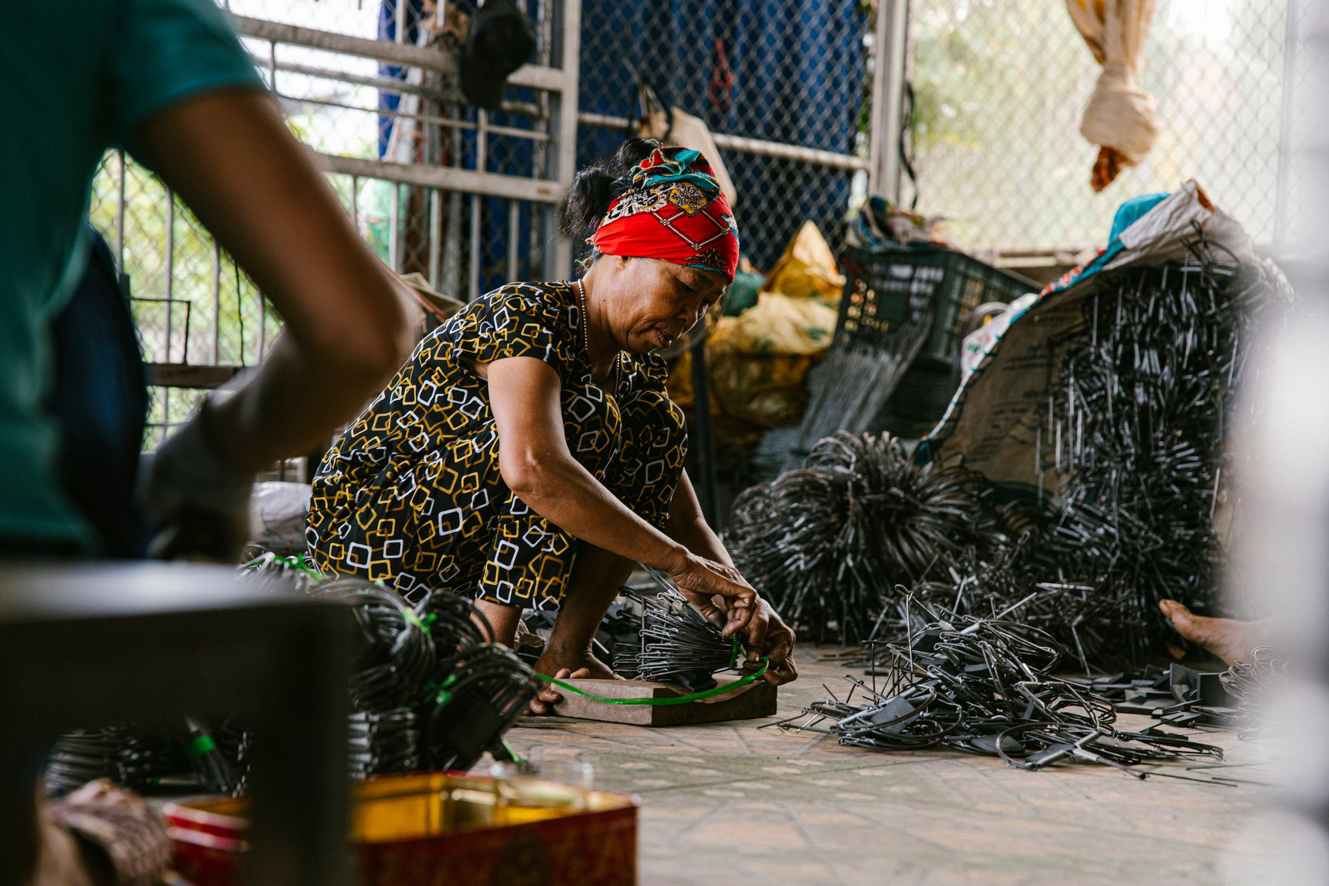 Focused woman working in a recycling center sorting metal parts on the floor.