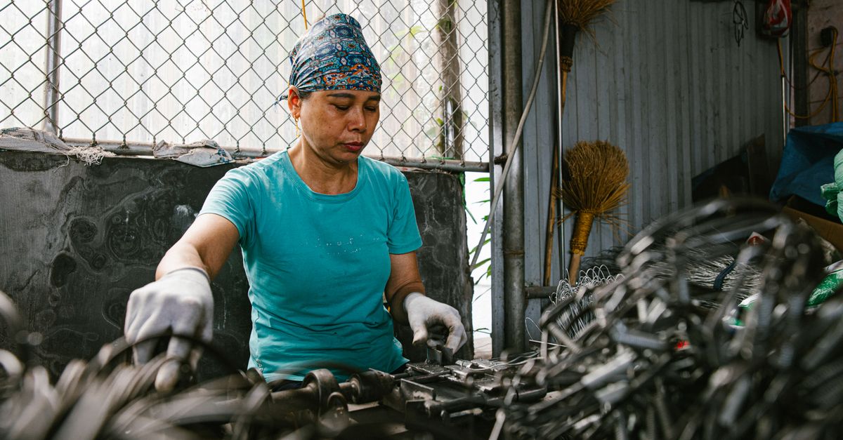 A recycling worker carefully sorting metal in a materials recovery facility