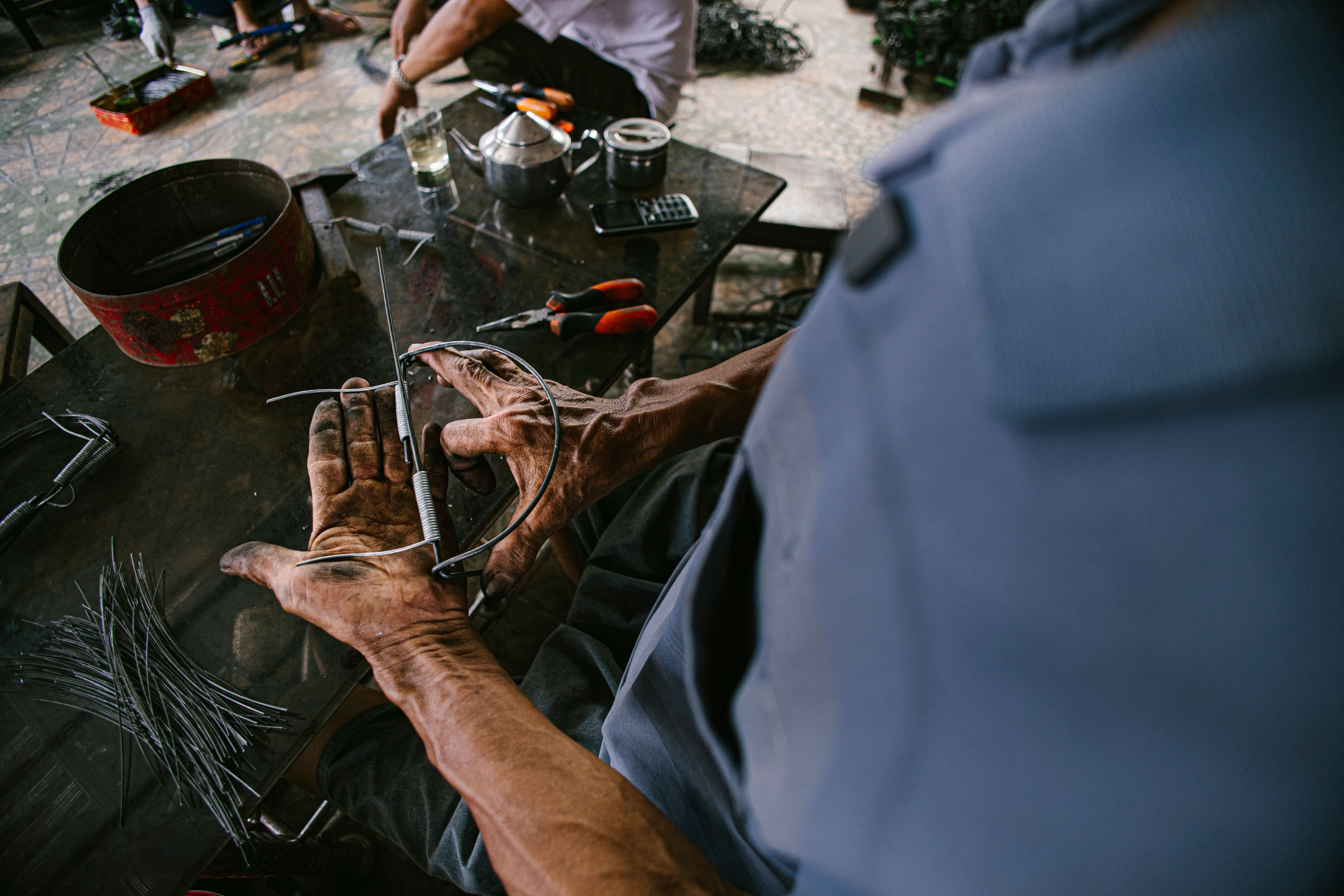 A skilled artisan shaping metal by hand in an industrial workshop setting.