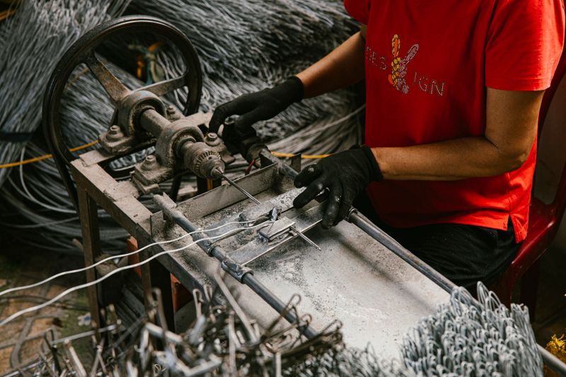 A person in a workshop uses a wire bending machine