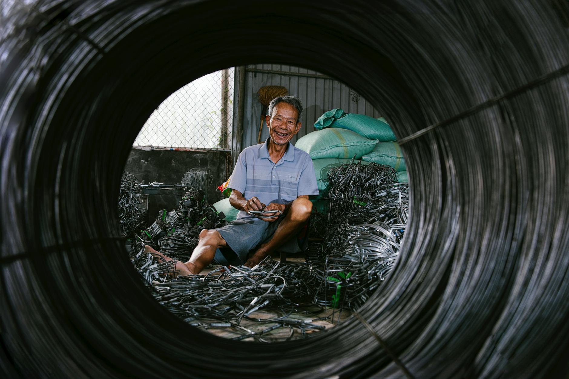 Portrait of a senior man smiling while handling wires in an industrial setting.