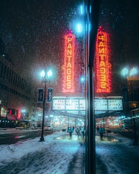 Snowy winter night scene at Pantages Theater with neon lights in downtown Minneapolis.