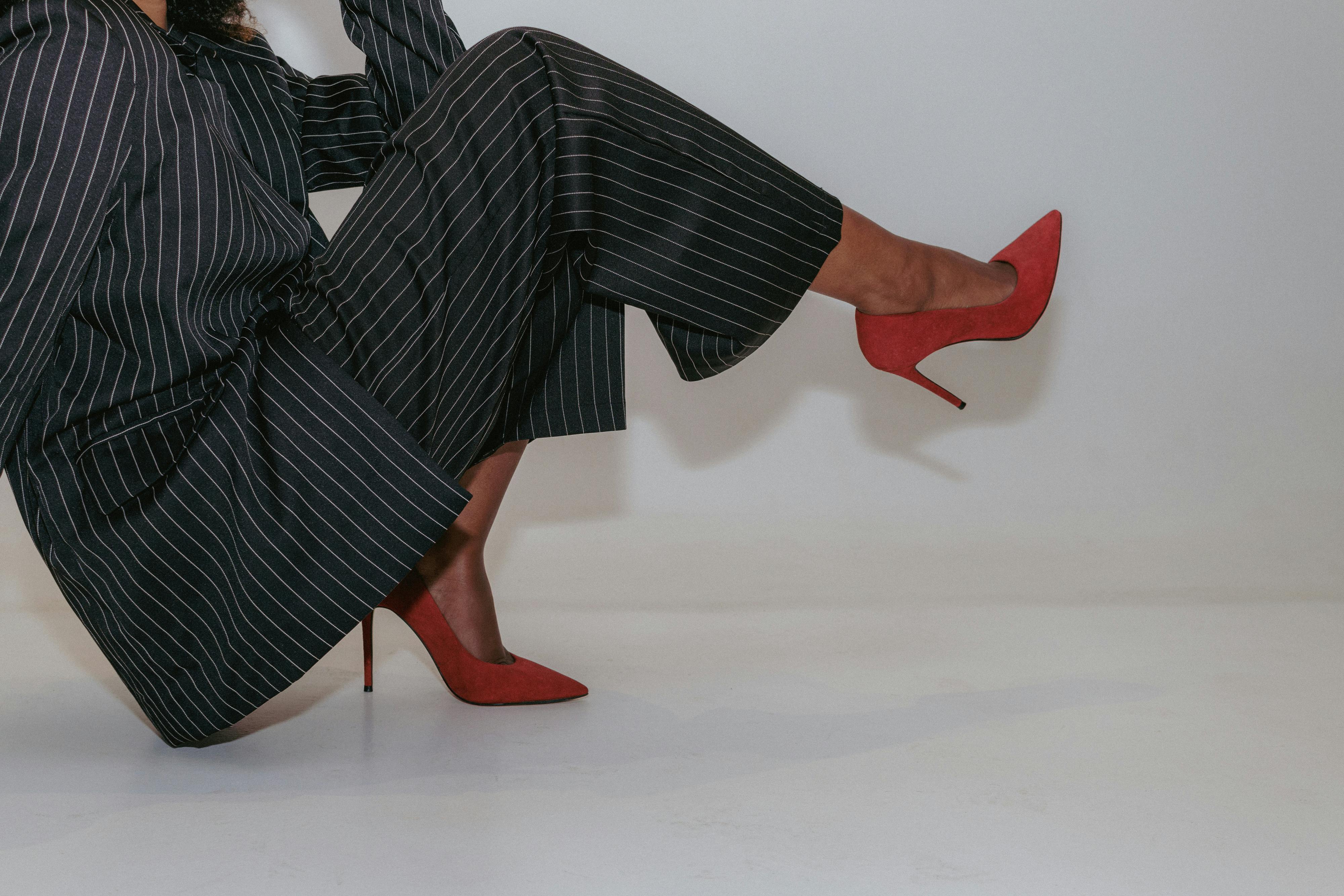 Stylish woman's legs in a pinstripe suit and red heels. Modern fashion statement.