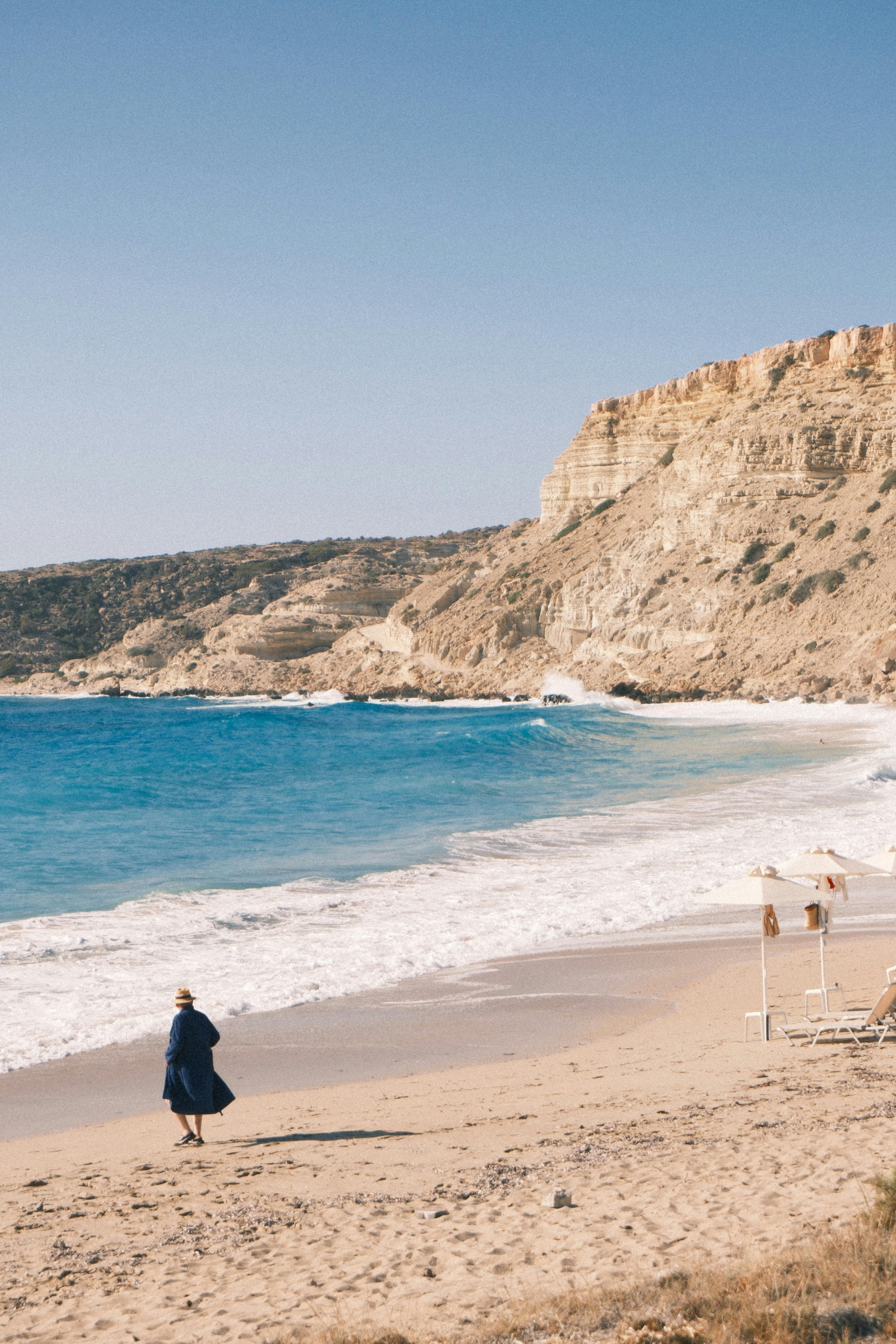 独自行走在宁静的海滩上，岩石悬崖和蔚蓝的海浪相伴