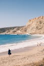 独自行走在宁静的海滩上，岩石悬崖和蔚蓝的海浪相伴