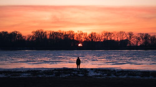 免费 人在日落时站在海滩上的剪影 素材图片