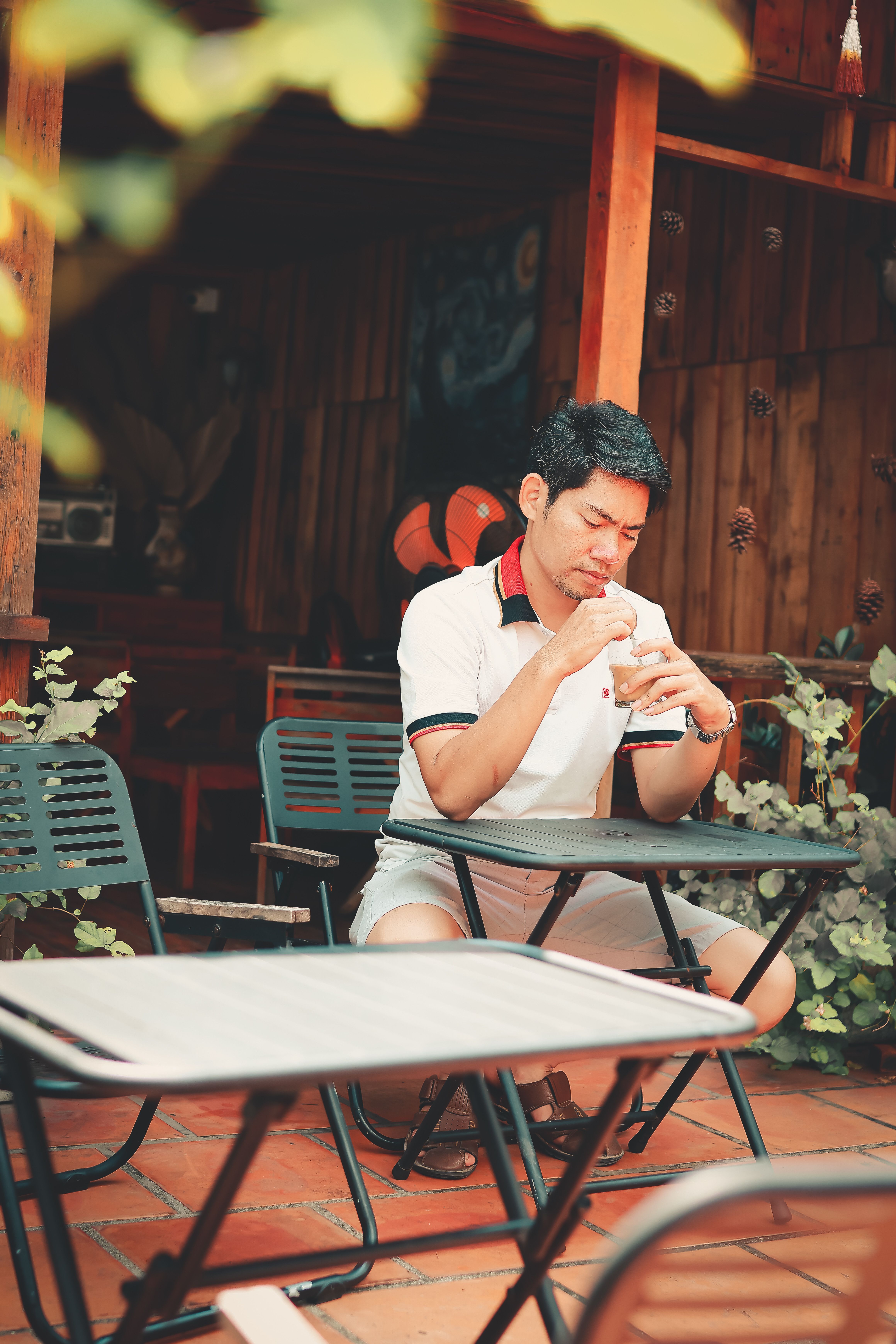 Casual man sipping beverage at an outdoor cafe, enjoying a peaceful moment.