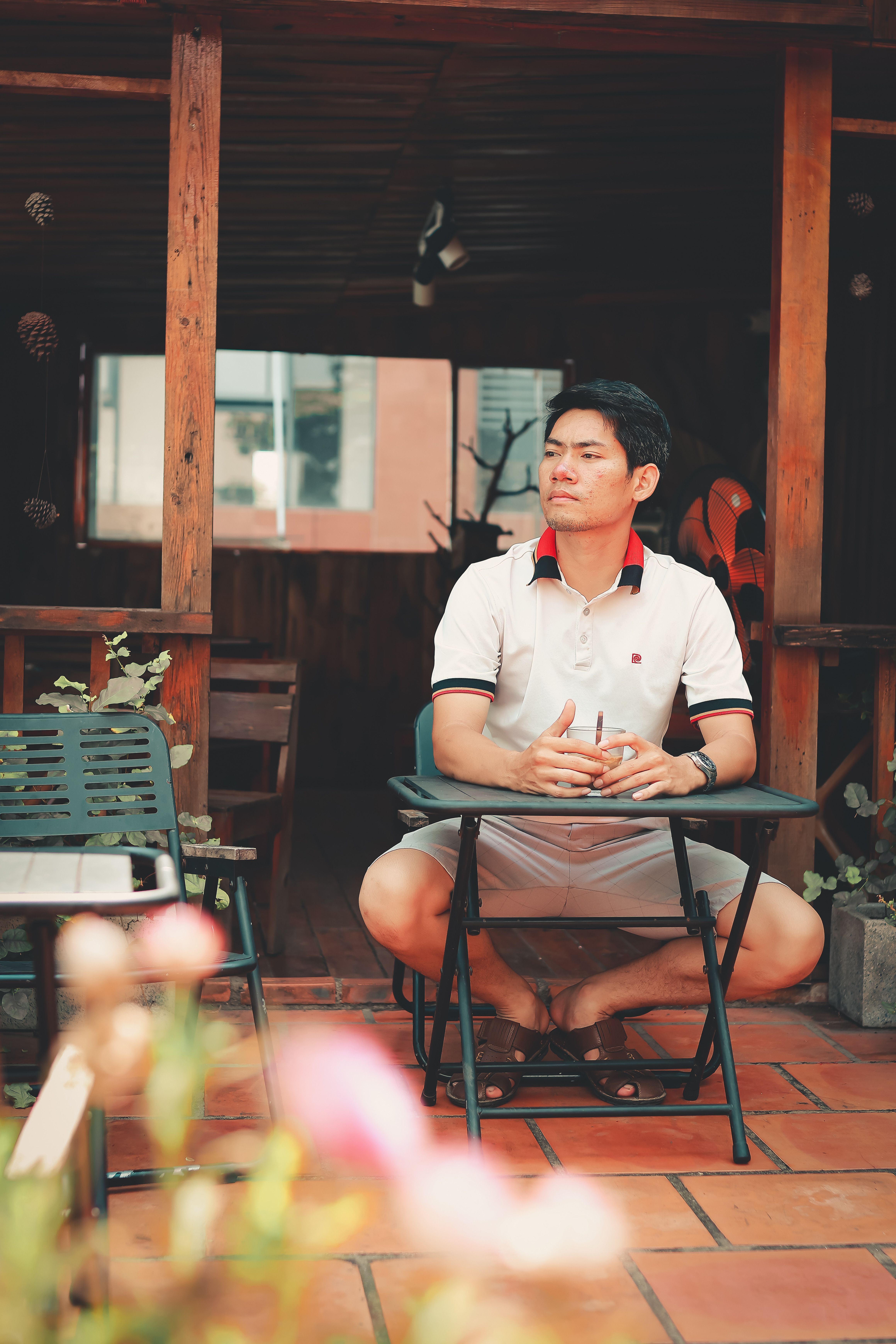 Adult man seated on a patio with rustic decor, enjoying a peaceful moment outdoors.