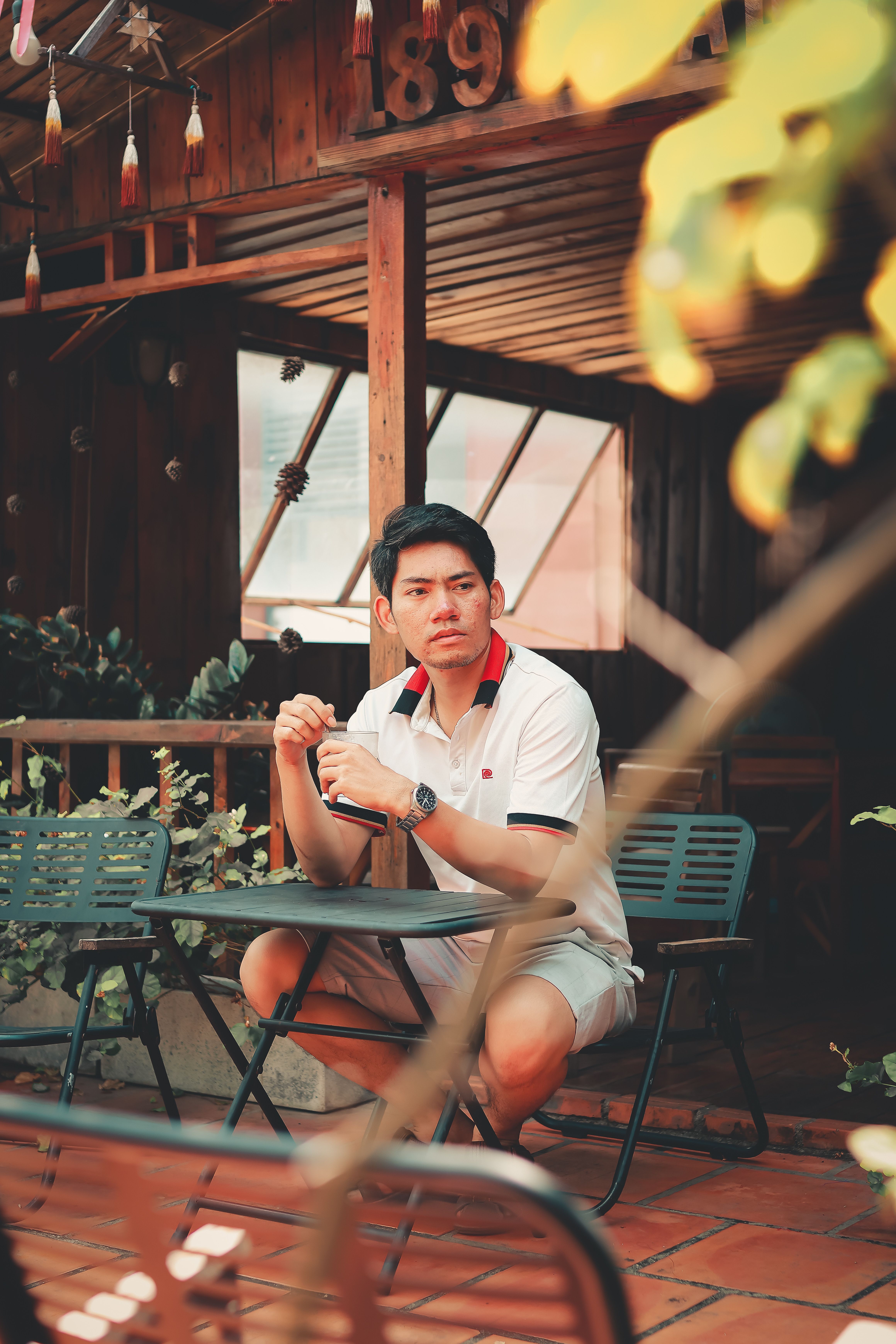 A man in casual attire enjoying a relaxed moment in a rustic outdoor patio with wooden features.