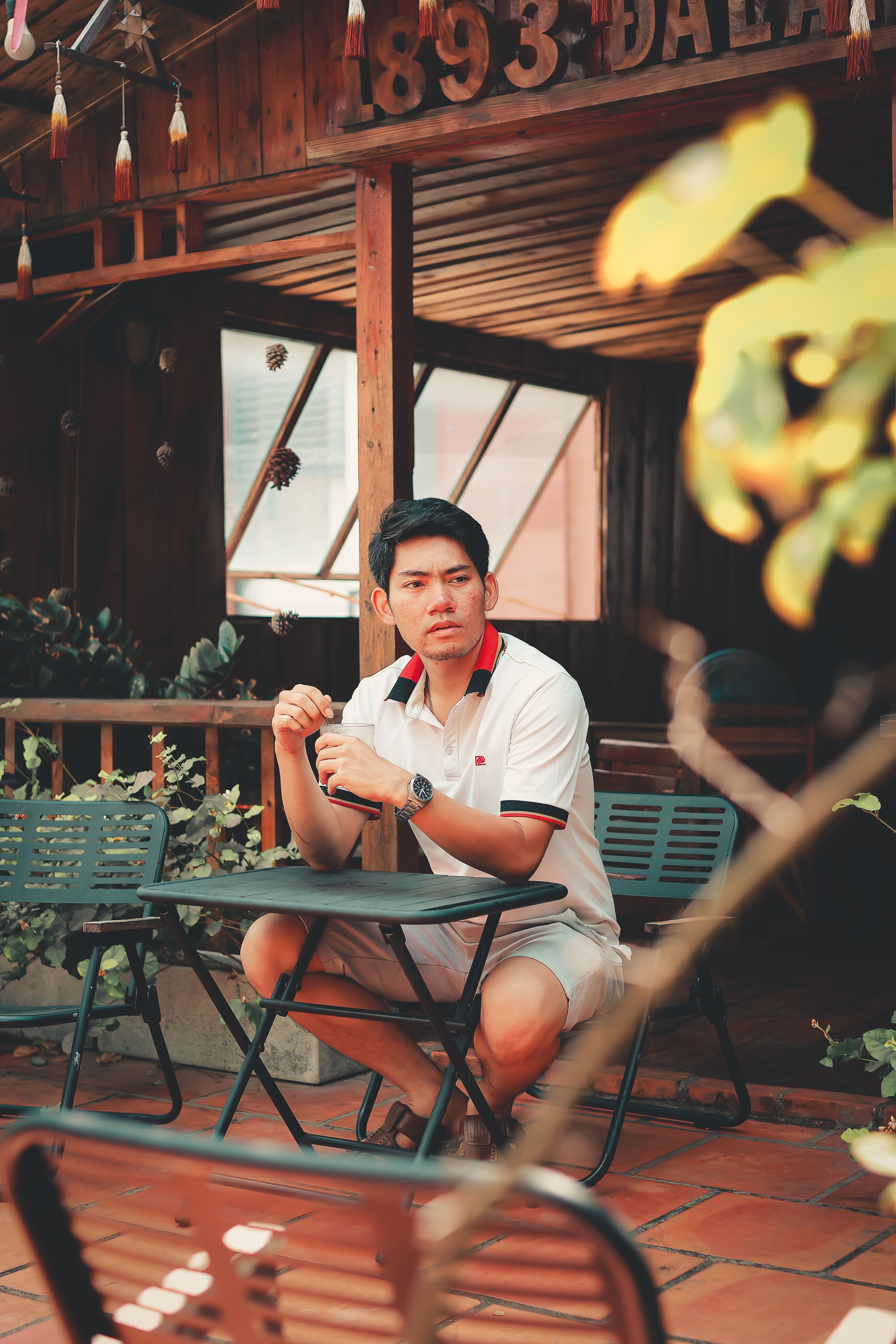 Man sitting at outdoor cafe table in relaxed summer ambiance.