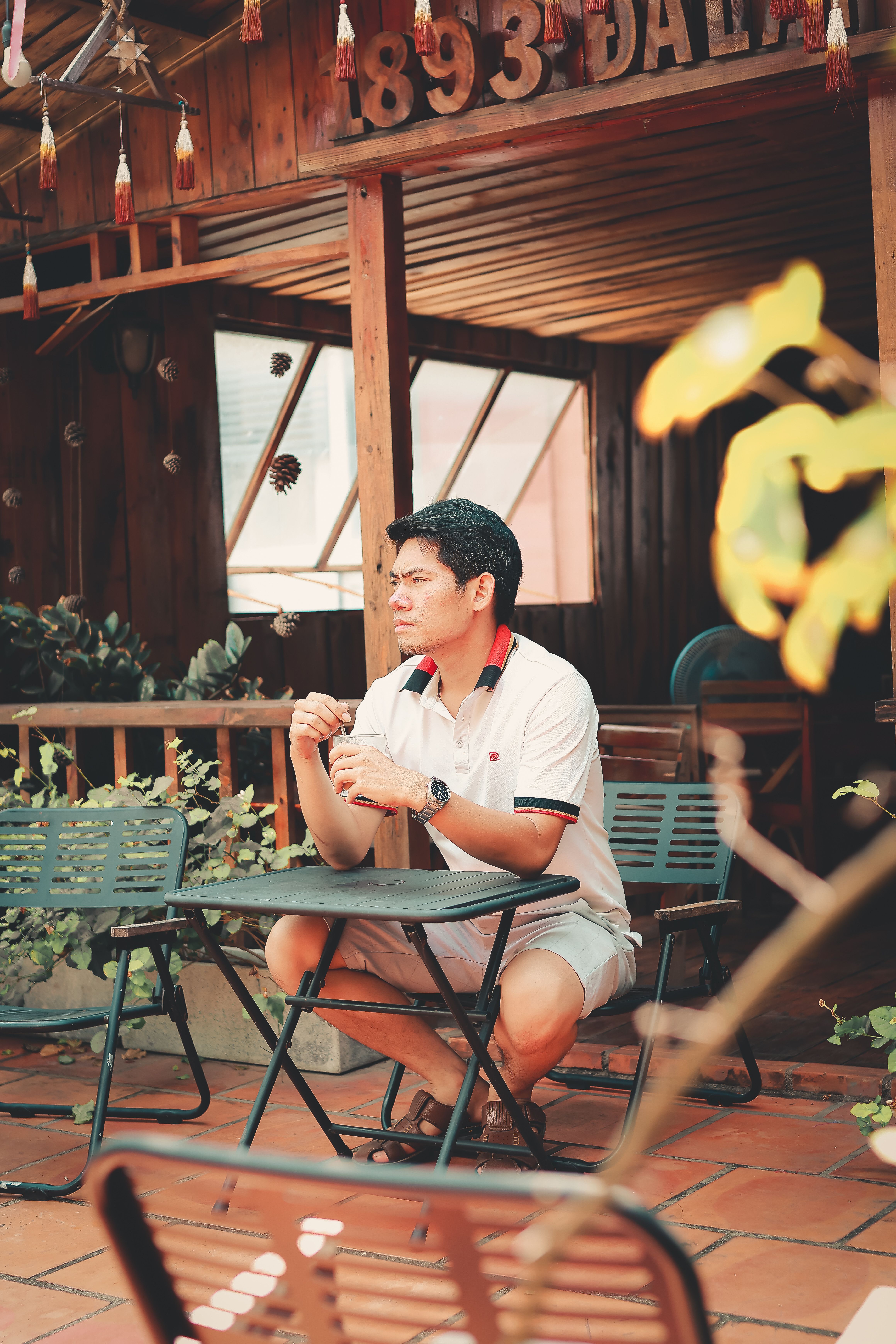 Man enjoying a meal in a sunlit rustic outdoor café setting, casual atmosphere.
