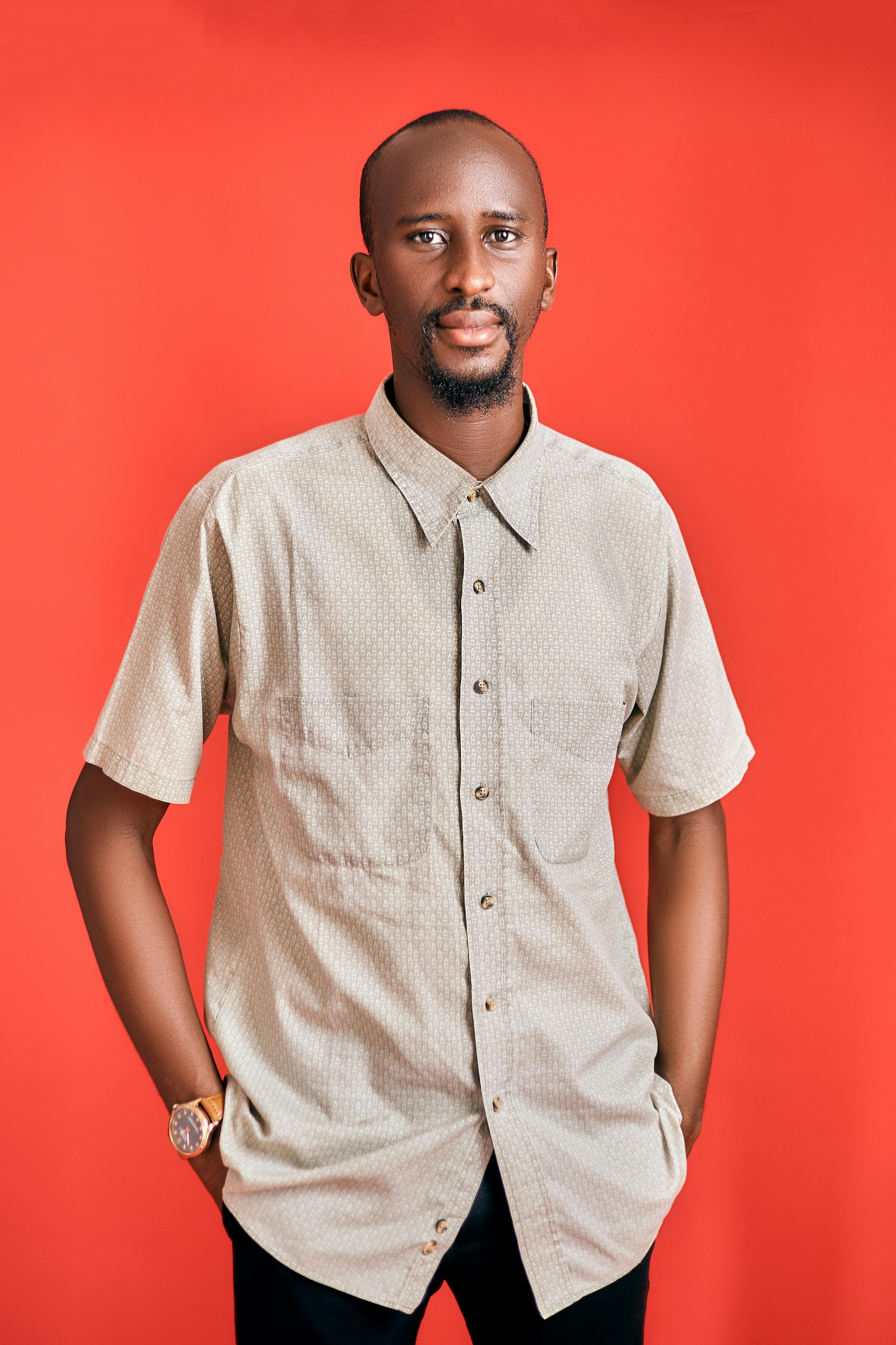 A man in a casual shirt poses against a vibrant red background.