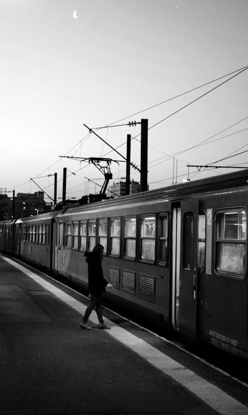Monochrome Photo of Person Standing Beside Train