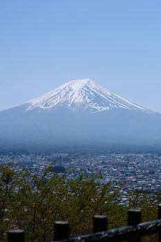 Breathtaking spring view of Mount Fuji towering above a nearby town with clear blue skies.