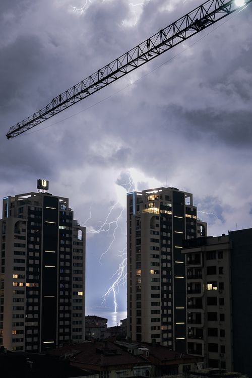 Free Lightning illuminates skyscrapers under dramatic night sky in urban setting. Stock Photo
