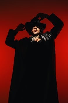 Avant-garde portrait of a stylish man in a hat against a red background.