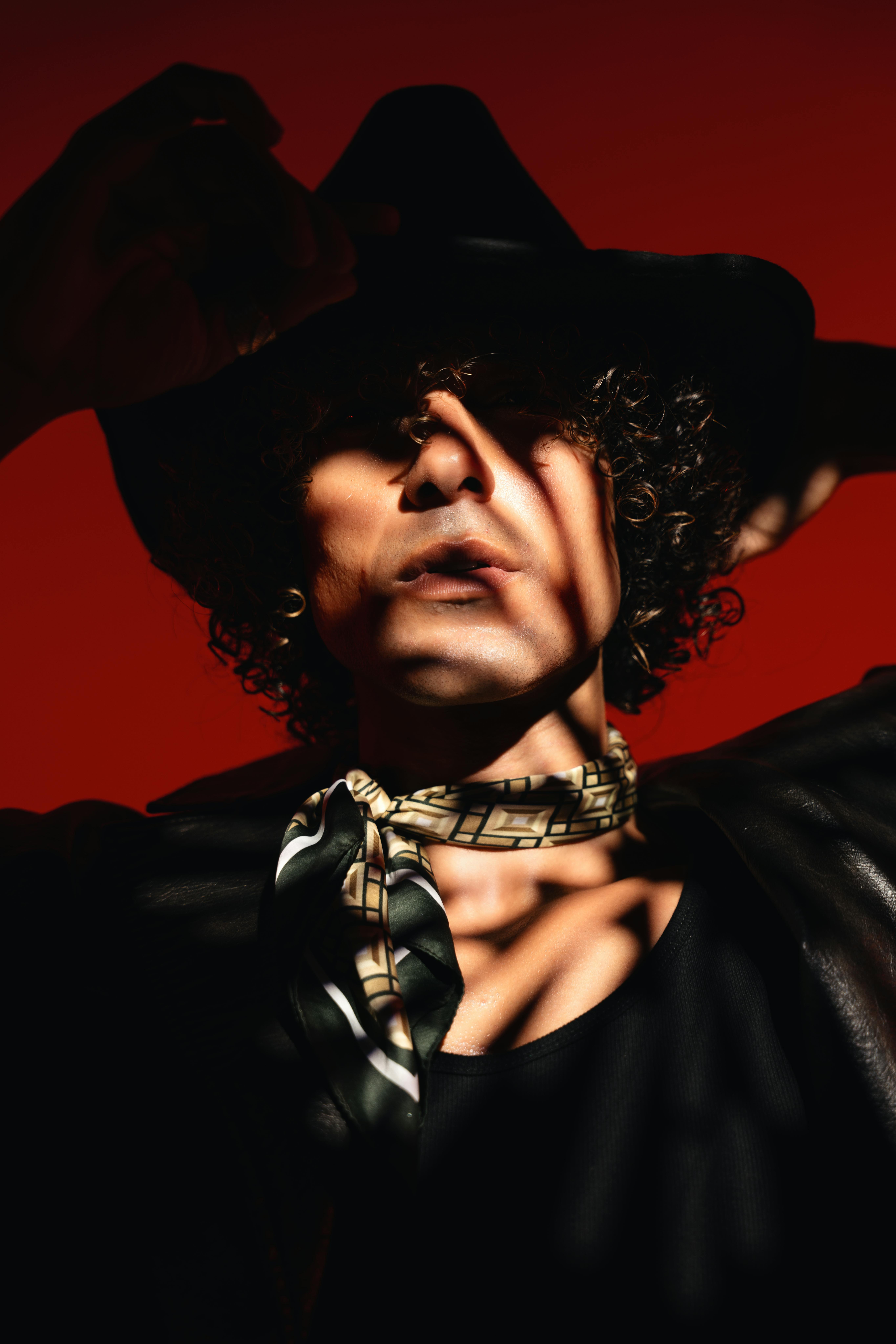 Artistic portrait of a stylish man with creative lighting and shadow play, set against a red background in London.