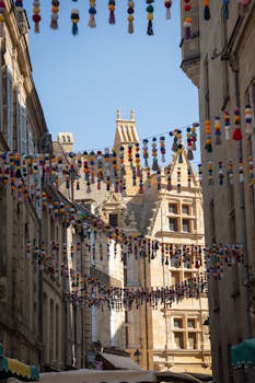 Festive pom-pom garlands adorn a charming street in Sarlat-la-Canéda, a historic village in Nouvelle-Aquitaine, France.