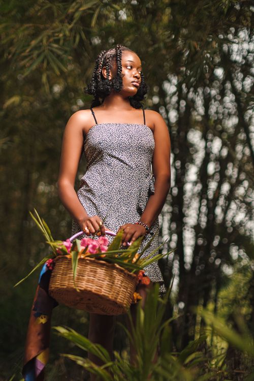 Free Young woman holding a flower basket in a vibrant forest setting, conveying nature's beauty. Stock Photo