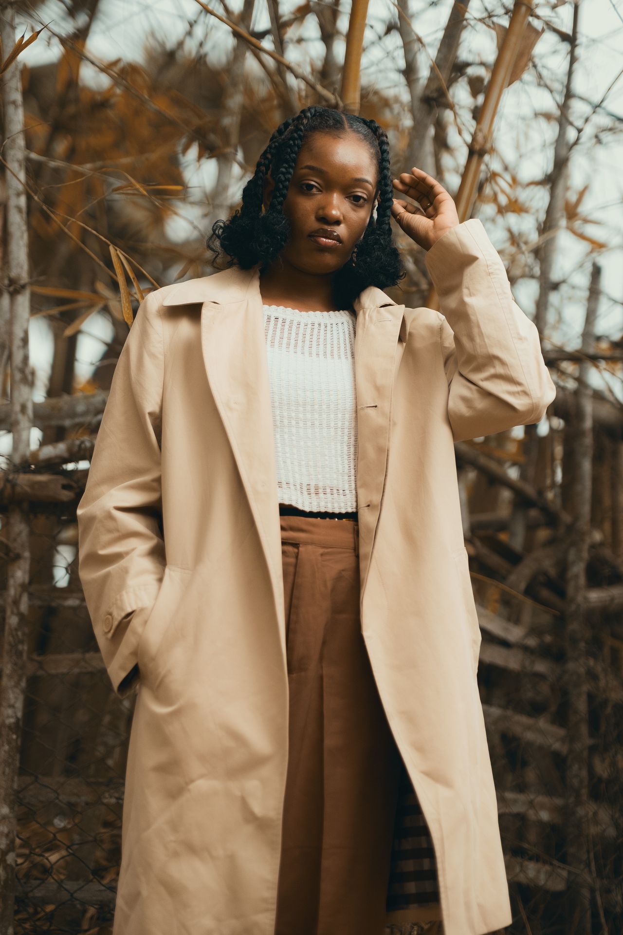 Beige trench coat layered over a white knit top and brown trousers in autumn