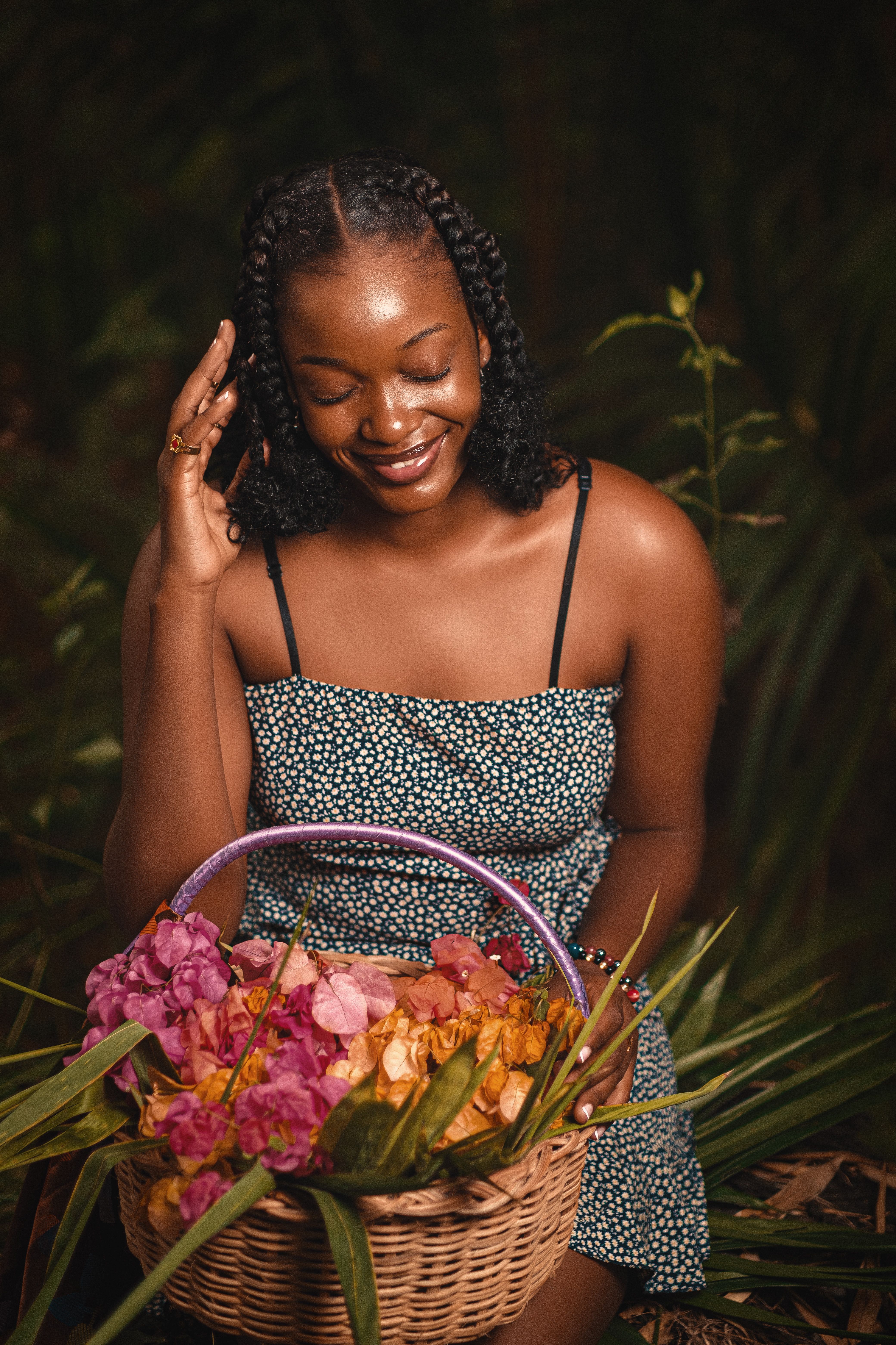 Joyful woman sitting outdoors with a basket of colorful flowers, radiating happiness.