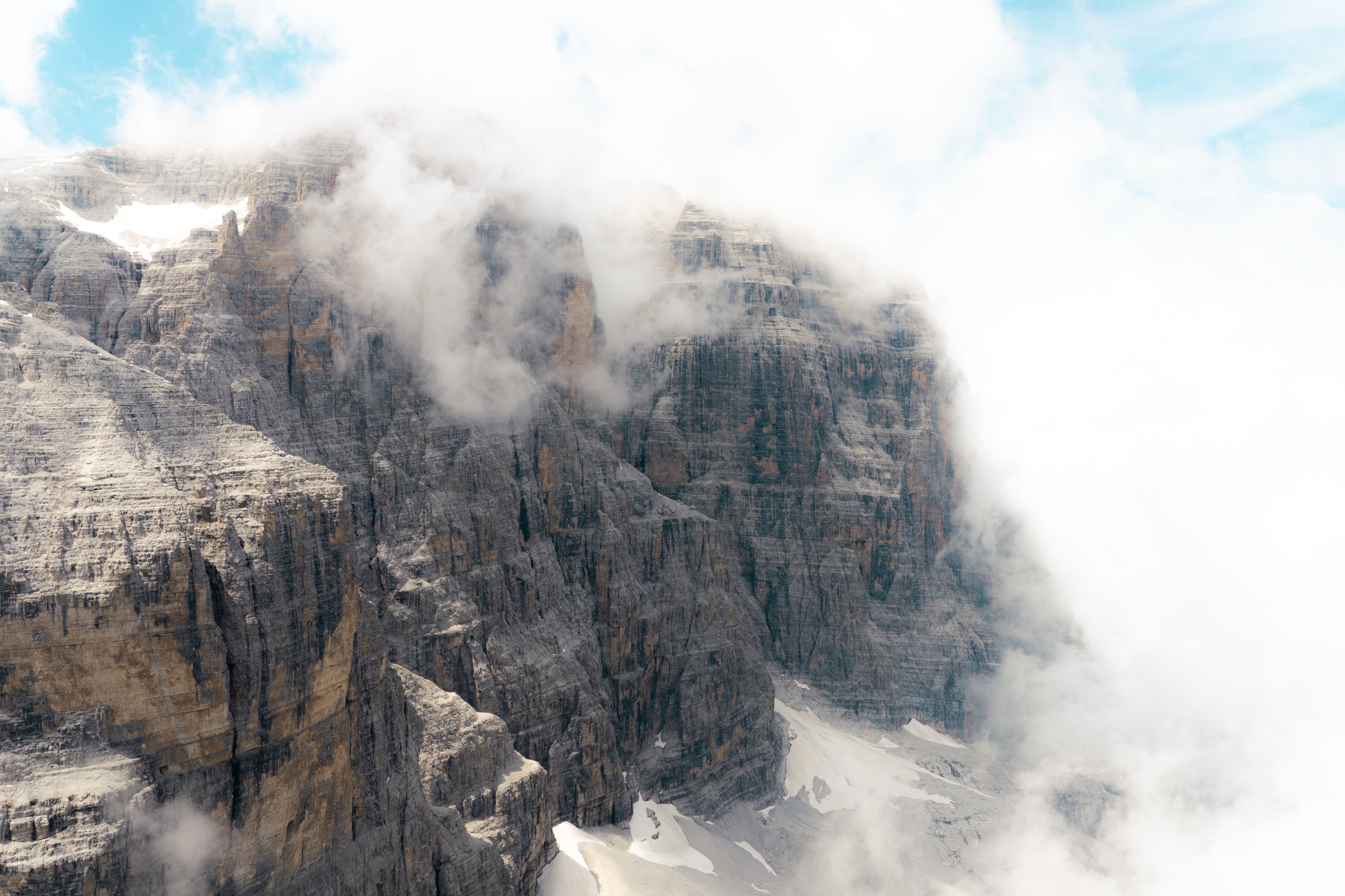 Breathtaking view of the misty Dolomites enveloped in clouds, showcasing rugged cliffs and serene nature.