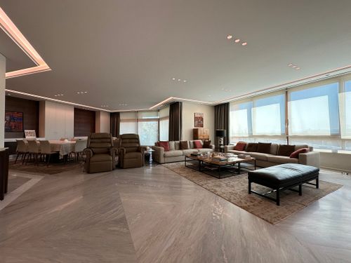Free Elegant and spacious modern living room with panoramic windows, stylish furniture, and warm lighting, creating a cozy ambiance. Stock Photo