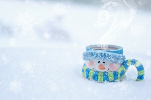 A snowman mug filled with steaming hot cocoa nestled in a snowy winter setting.