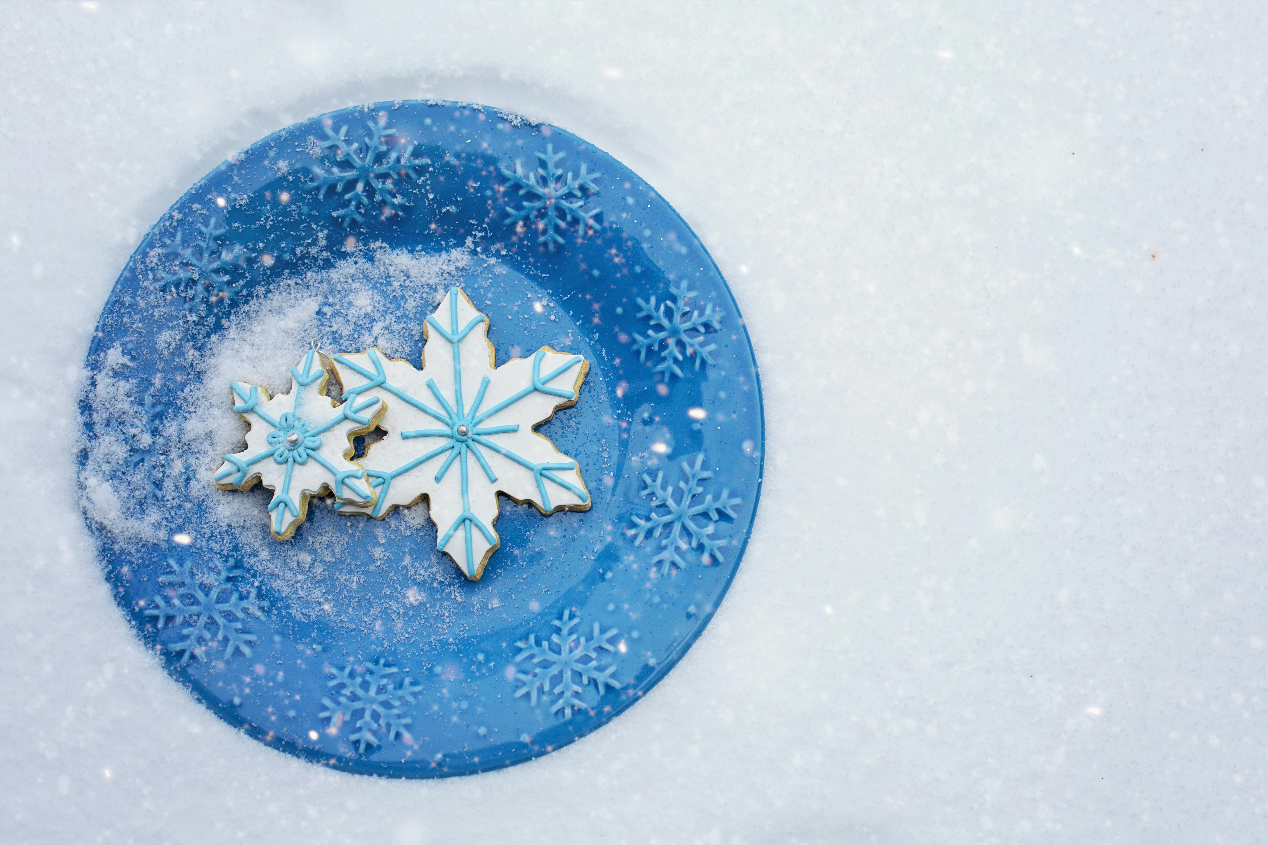 蓝色盘子里盛着雪花形饼干，背景是雪景，完美契合圣诞节