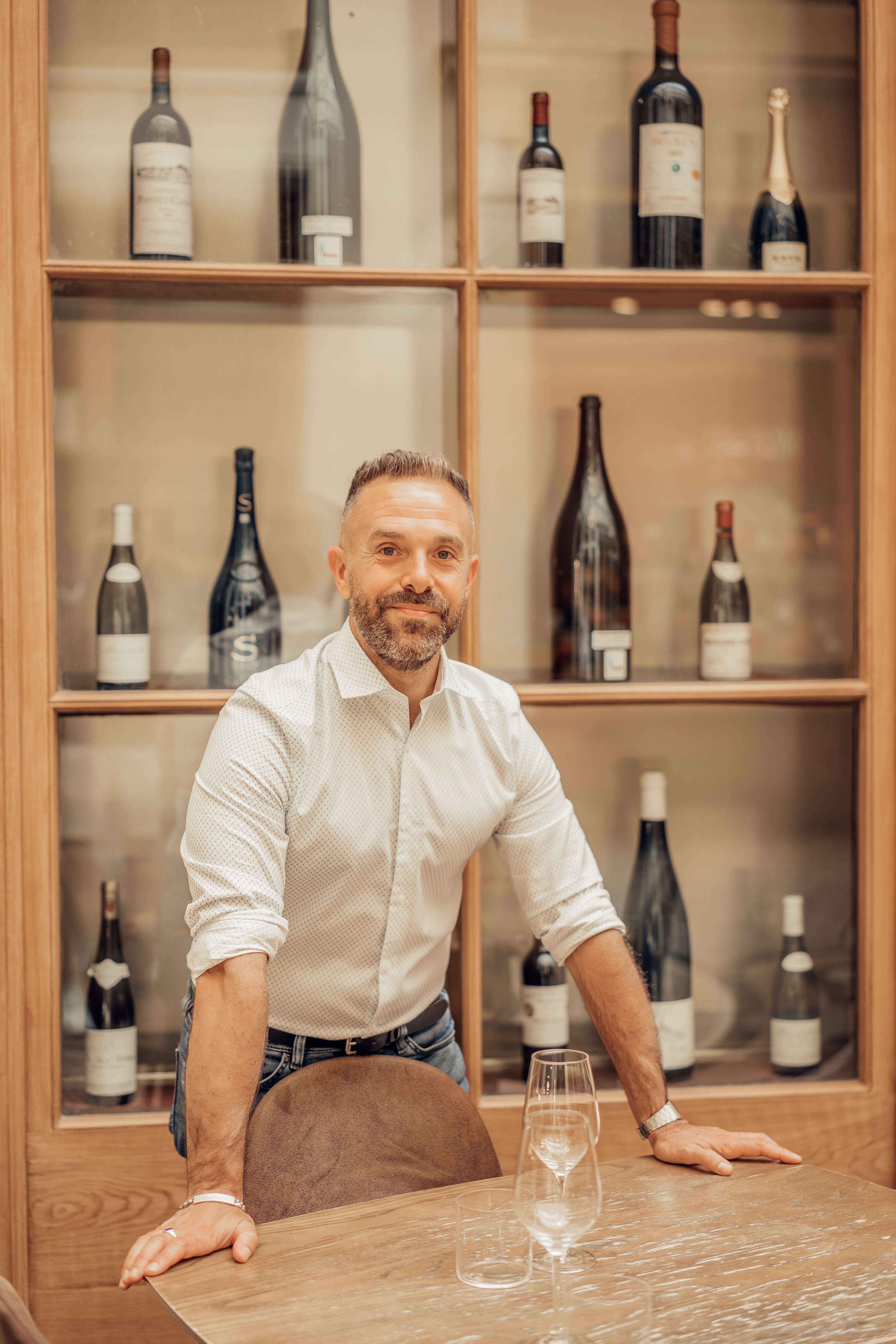 Stylish man standing by wooden racks with wine bottles, Paris.
