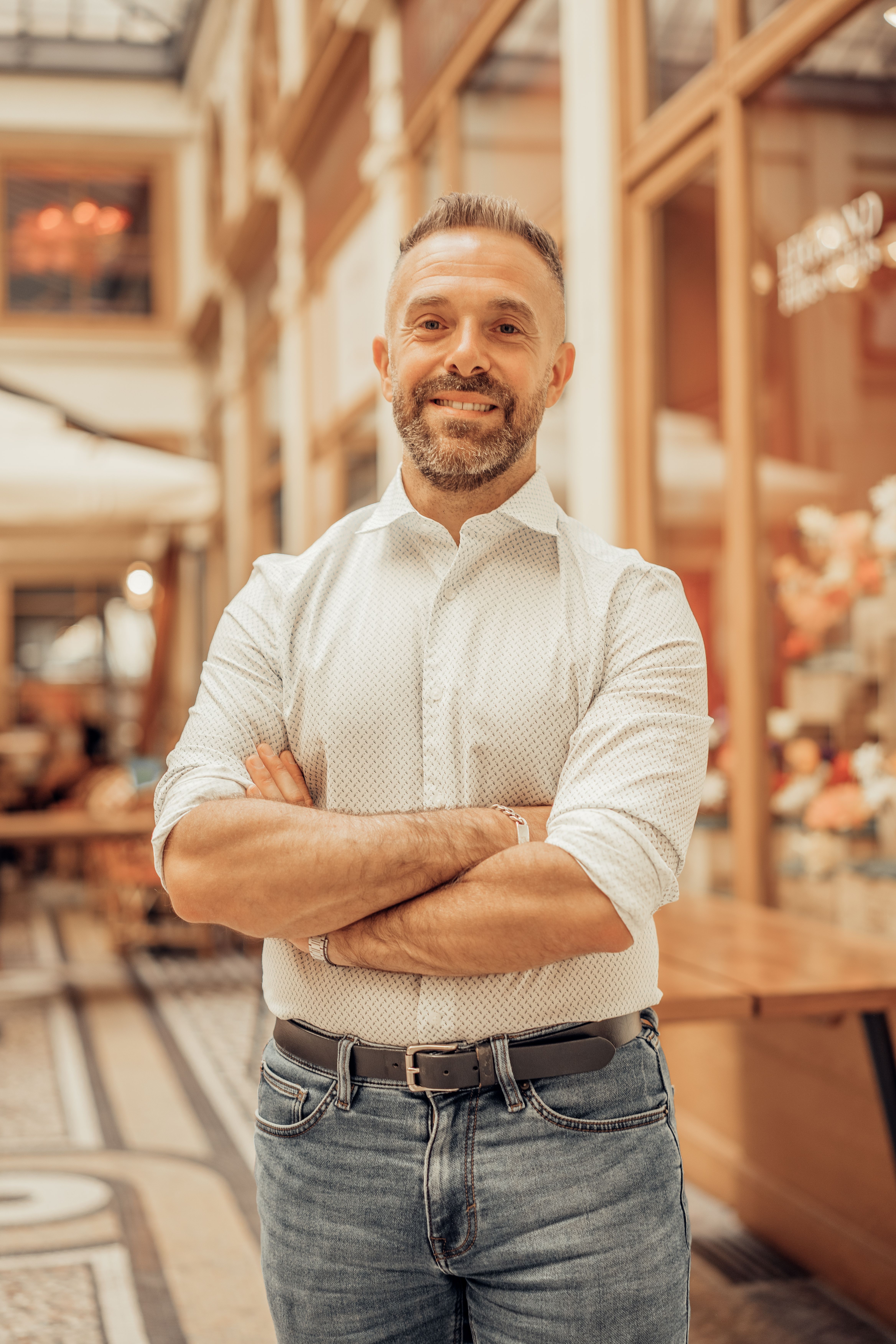 Smiling man in a white shirt poses confidently indoors at a stylish Paris location.