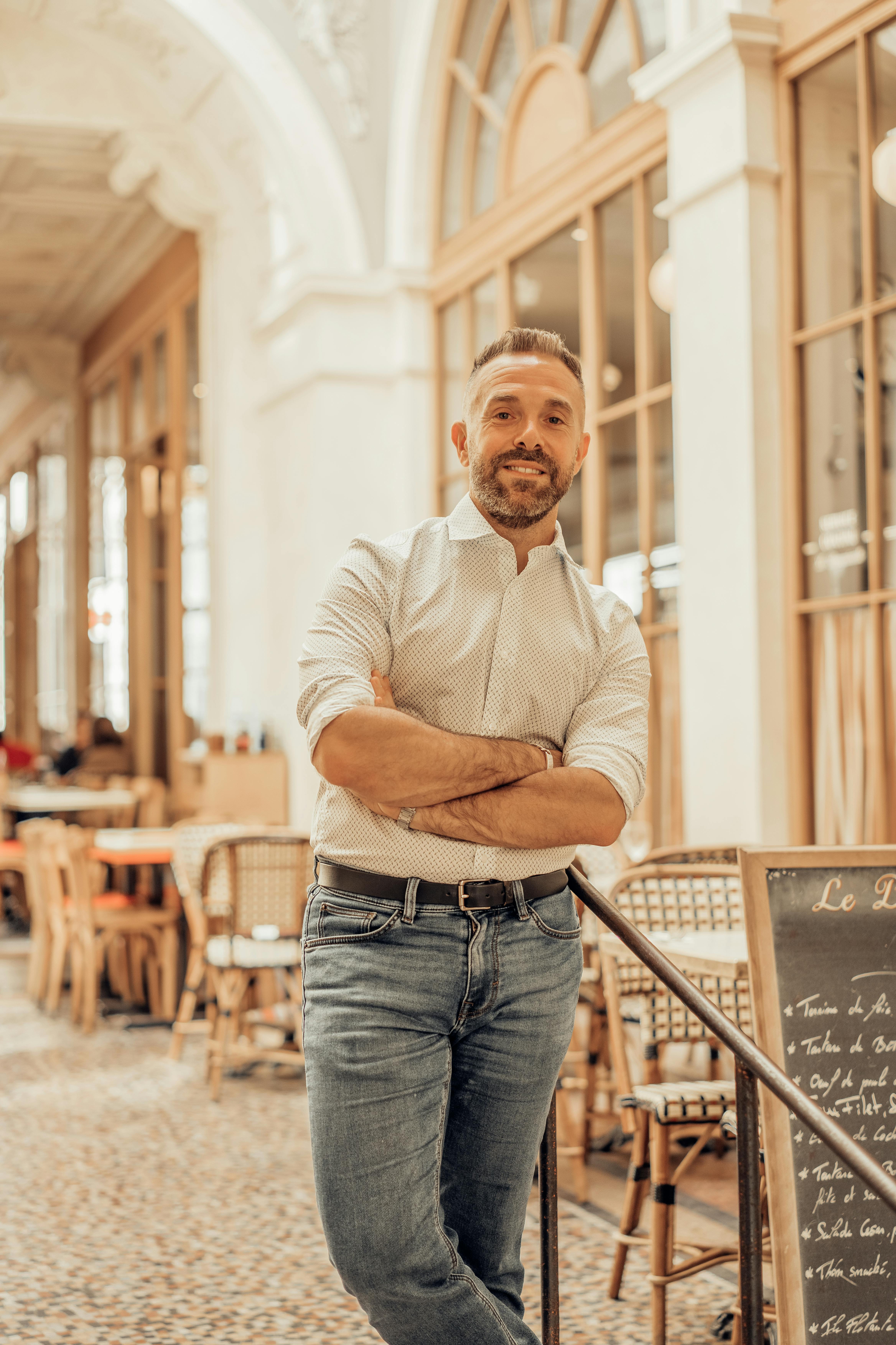 A man stands confidently in a stylish Paris café, exuding a relaxed vibe.