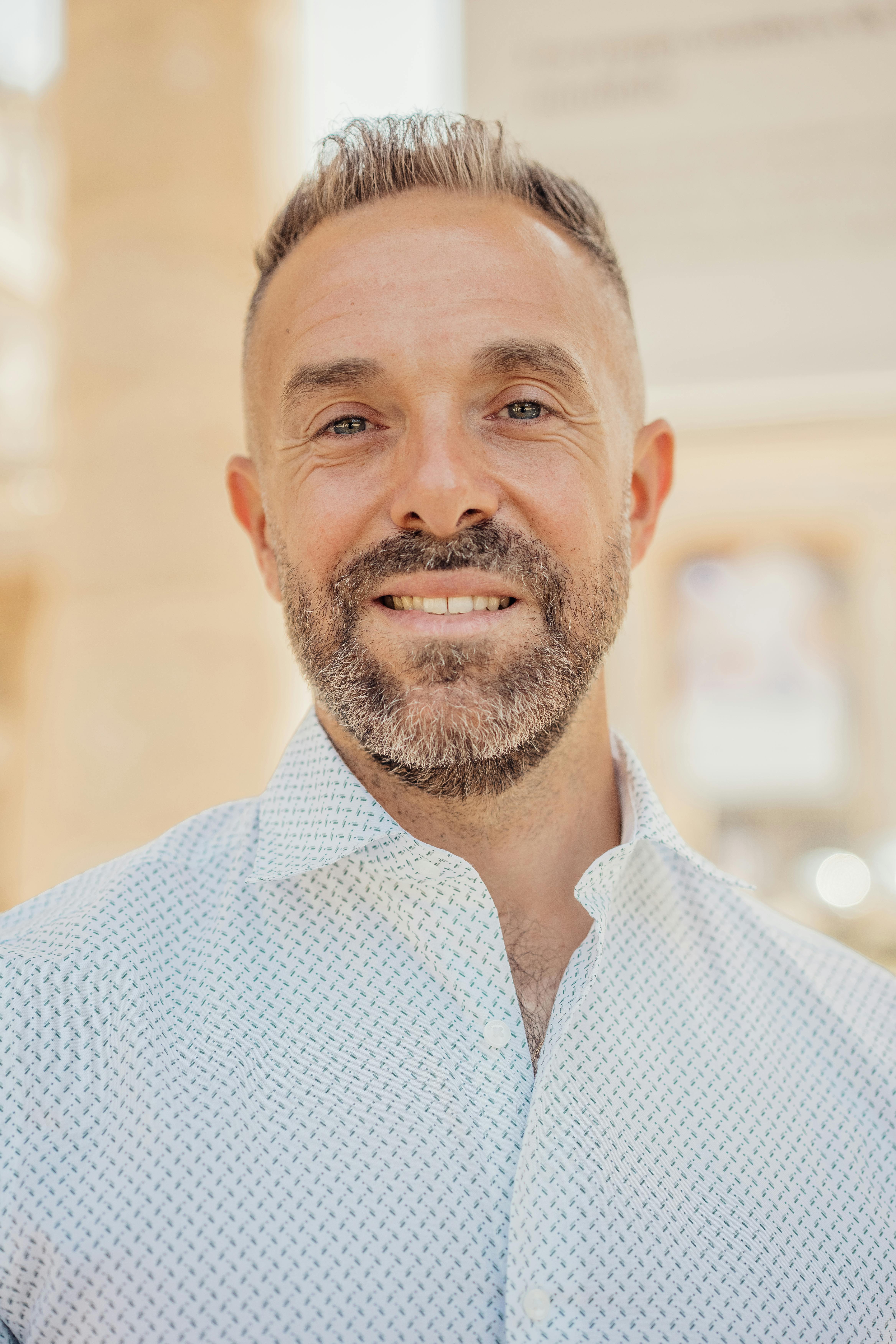 Portrait of a smiling man with a beard in Paris, France, outdoors on a sunny day.