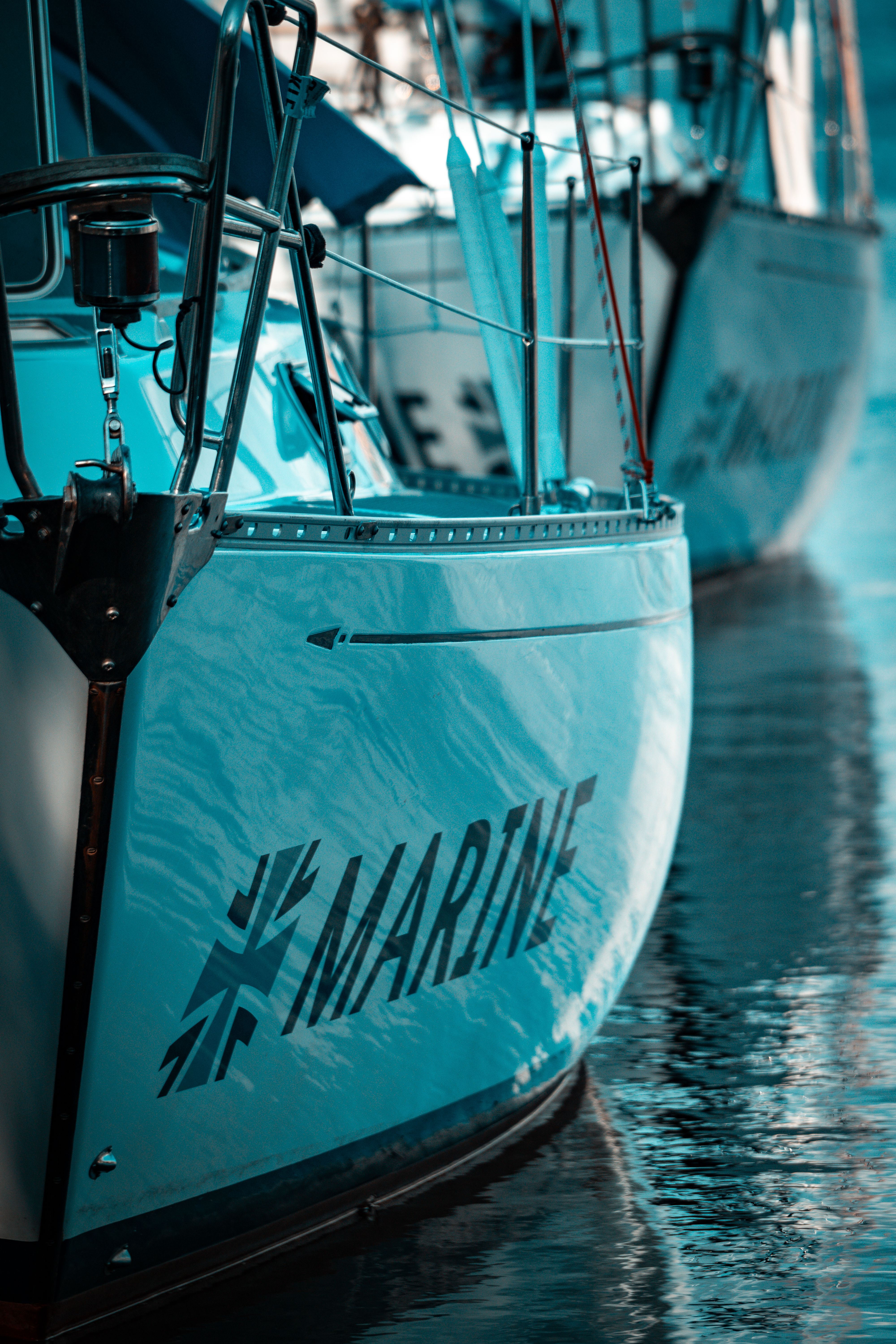 Close-up of a sailboat with 'MARINE' text docked at a marina, reflecting on calm water.
