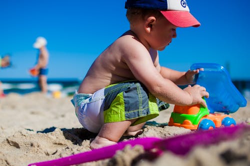 Toddler Playing Plastic Toy Car on Beach