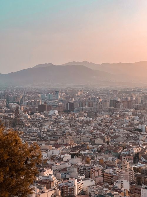 Free Stunning sunset view of Málaga cityscape with mountain range backdrop. Stock Photo