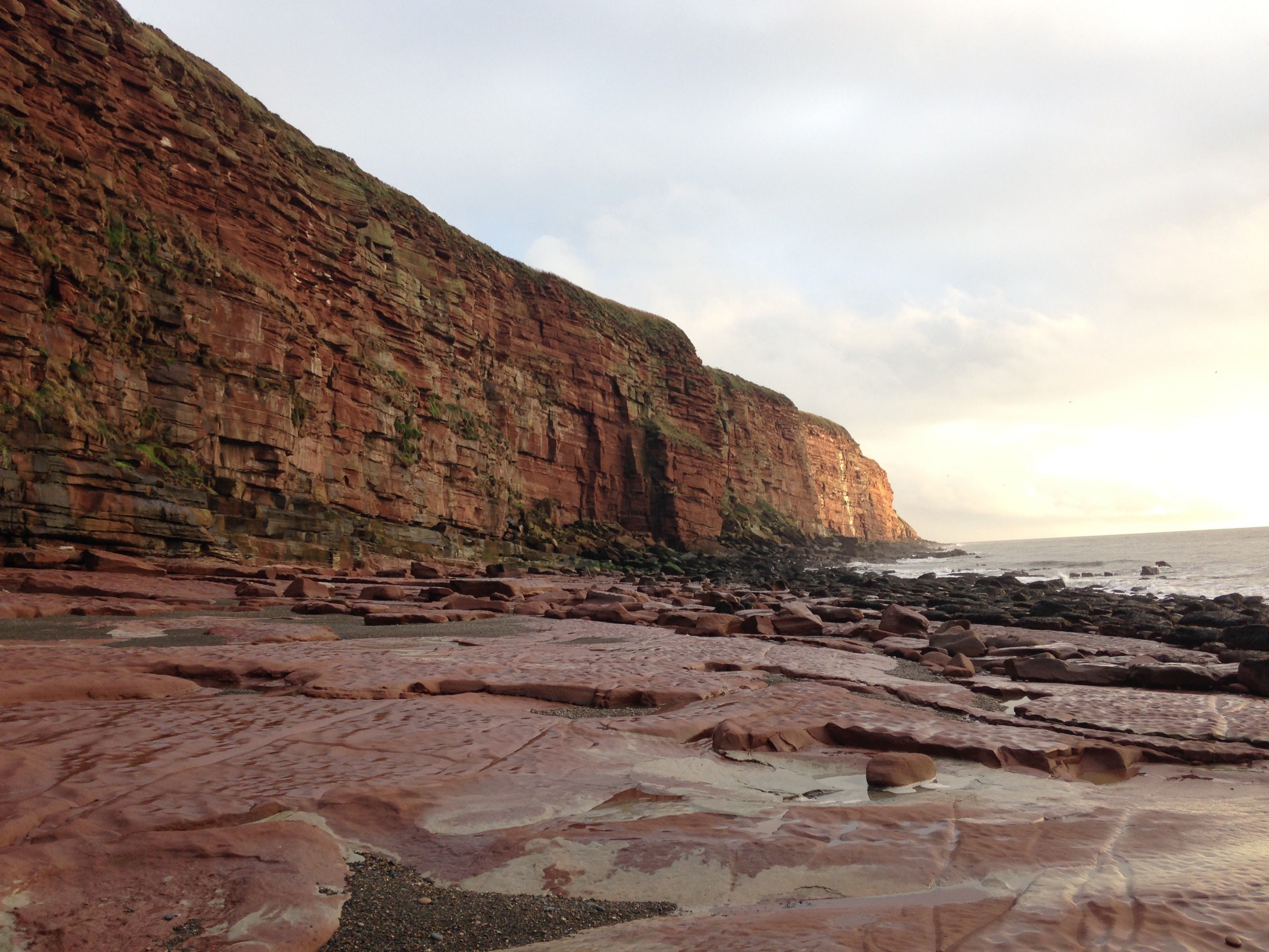 Majestic red sandstone cliffs along the St. Bees headland at sunset on the Cumbrian coast.