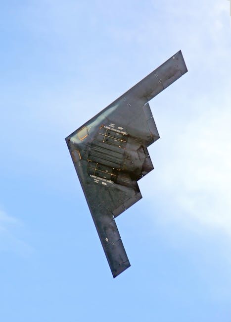 A sleek stealth bomber soars through a clear blue sky, showcasing advanced military aviation.
