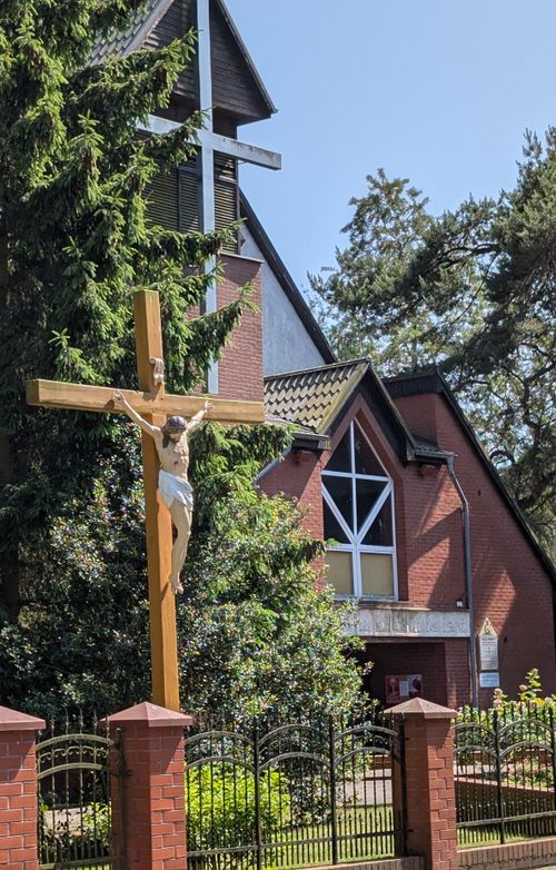 Free A scenic church view in Swinoujscie, Poland, featuring a crucifix and lush greenery. Stock Photo